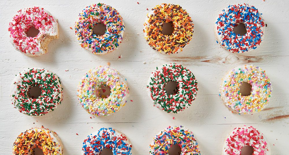 A bunch of donuts with different colored sprinkles on them