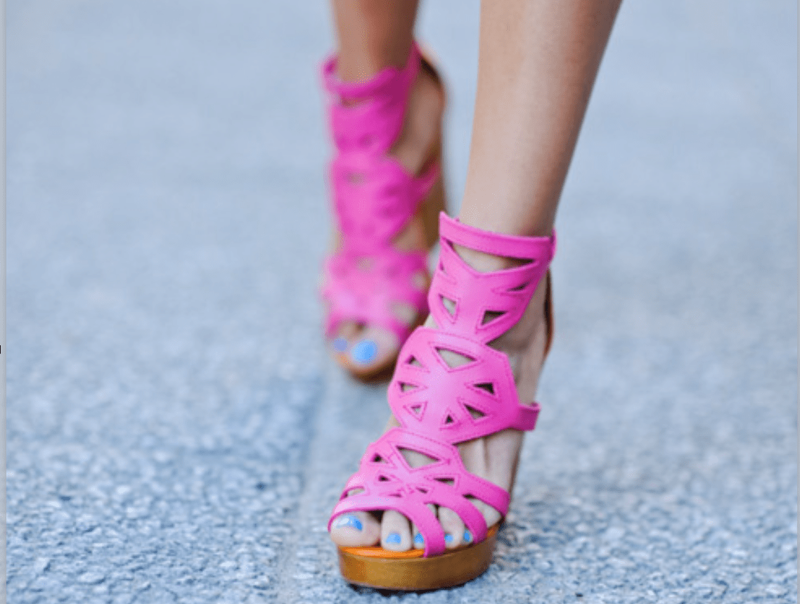 A close up of the feet of a person wearing pink shoes.