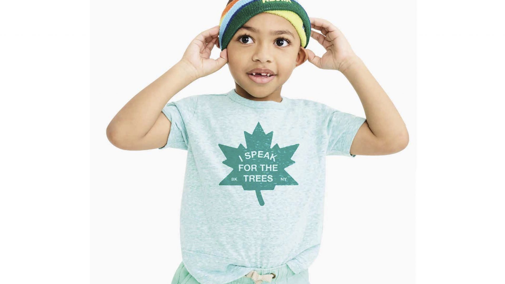 A young boy wearing a headband and shirt with the words 
